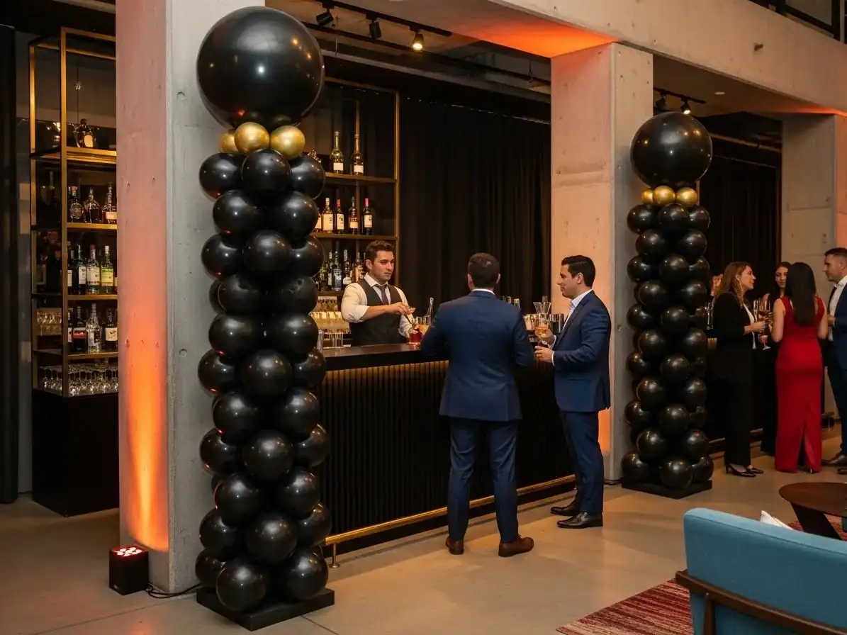Columnas de globos negro y dorado en el lounge bar de un evento corporativo elegante