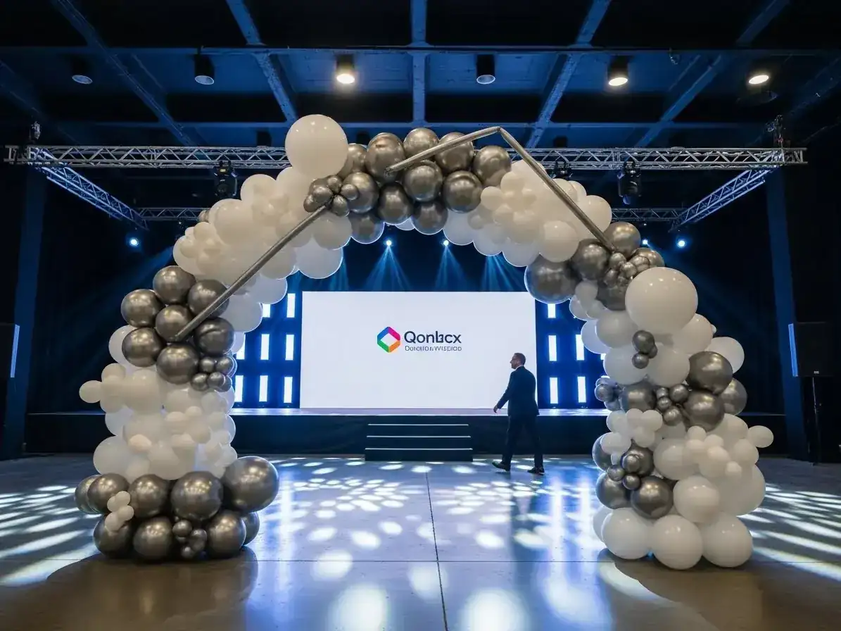 Arco de globos blanco y plateado sobre escenario con pantalla de proyección en conferencia empresarial
